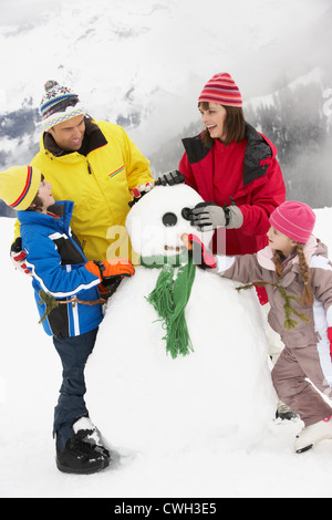 Familie Gebäude Schneemann auf Ski-Urlaub In Bergen Stockfoto