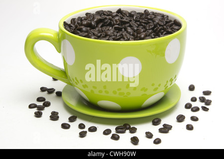 Yellow Polka Dot Kaffee Becher gefüllt mit Kaffeebohnen auf weißem Hintergrund Stockfoto