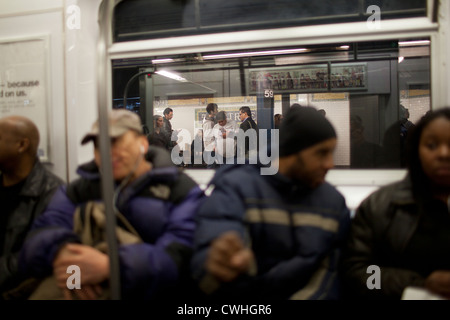 Pendler sitzen in einer u-Bahn-Wagen, wie es in einer Station auf der Upper East Side von New York City zieht. Stockfoto