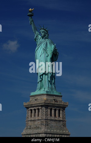 Die Freiheitsstatue im Hafen von New York auf Sockel mit Fackel gegen ein strahlend blauer Himmel empor gehalten. Stockfoto