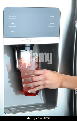 Nahaufnahme einer Womans Hand hält ein Glas, Wasser und Eis Dispenser eines modernen Kühlschranks Stockfoto