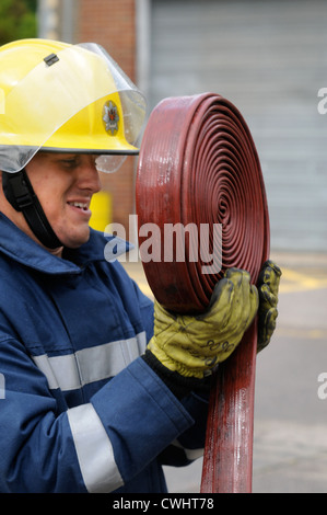 Ein Feuerwehrmann, wickeln Sie ein Schlauch während einer Übung mit weißen Uhr in Pontypridd Feuerwache in South Wales UK Stockfoto