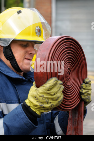 Ein Feuerwehrmann, wickeln Sie ein Schlauch während einer Übung mit weißen Uhr in Pontypridd Feuerwache in South Wales UK Stockfoto