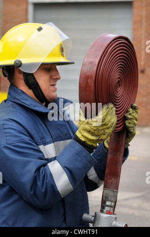 Ein Feuerwehrmann, wickeln Sie ein Schlauch während einer Übung mit weißen Uhr in Pontypridd Feuerwache in South Wales UK Stockfoto