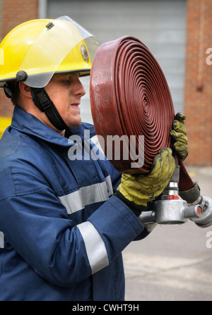 Ein Feuerwehrmann, wickeln Sie ein Schlauch während einer Übung mit weißen Uhr in Pontypridd Feuerwache in South Wales UK Stockfoto