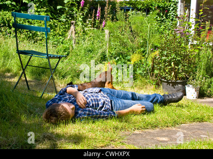 Teenager in einem Garten hinter dem Haus mit seinen Border Terrier Hund liegend Stockfoto