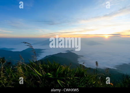 Sonnenaufgang am Horizont in Morgen am hohen Berg mit blauen Himmel bewölkt und Nebel Stockfoto