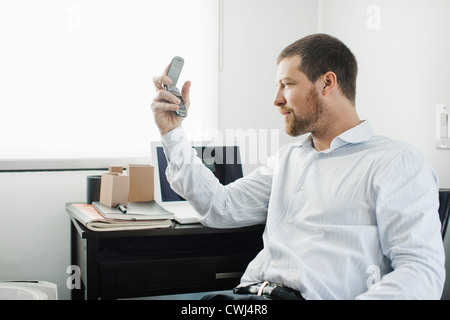 Kaukasische Geschäftsmann mit Handy am Schreibtisch Stockfoto