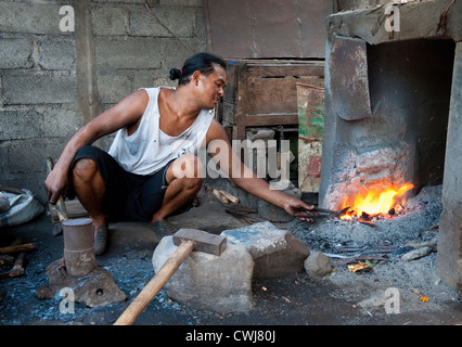 In einem Schmied Dorf in Bali, Indonesien schmiedet ein Mann einen Bauern ernten Sichel häufig gesehen in Reisterrassen. Stockfoto