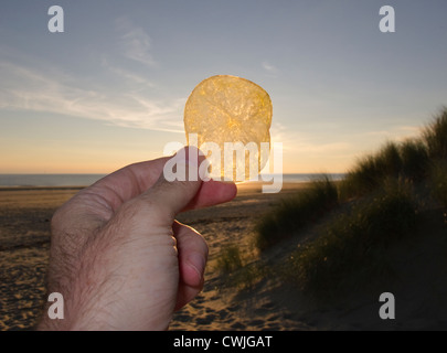 Eine Kartoffel gestochen scharfe Hilfe gegen die untergehende Sonne am Strand Stockfoto