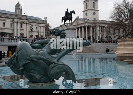 Meerjungfrau und Delfine Brunnen Skulptur auf dem Trafalgar Square mit Statue von George IV und Kirche St. Martin-in-the-Fields hinter Stockfoto