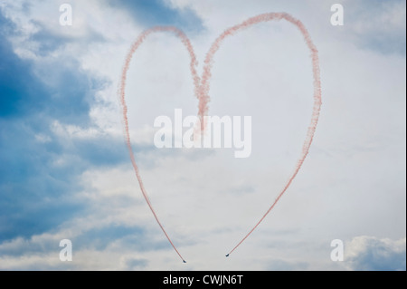 Rosa rauch Spuren von einer Antenne Kunstflug Team bilden eine liebe herz Symbol in den Himmel anzeigen. Konzept Bild Stockfoto