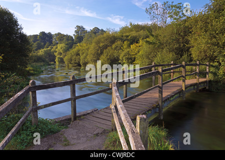 Alte hölzerne Fußgängerbrücke über den Fluss Itchen in der Nähe von Ovington in Hampshire aufgenommen kurz nach Sonnenaufgang an einem Sommer-morgen. Stockfoto