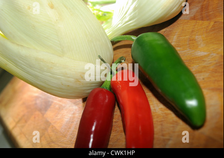 Fenchelknollen und Mischung von roten und grünen Chilischoten auf Schneidbrett aus Holz Stockfoto