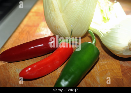 Fenchelknollen und Mischung von roten und grünen Chilischoten auf Schneidbrett aus Holz Stockfoto