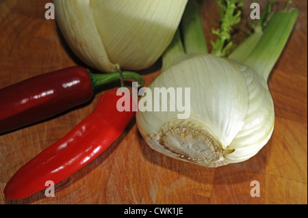 Fenchelknollen und Mischung von roten und grünen Chilischoten auf Schneidbrett aus Holz Stockfoto