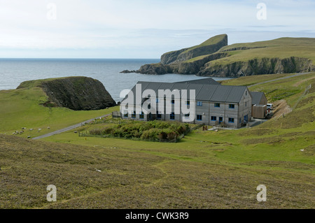 Fair Isle Bird Observatory in den Shetland-Inseln mit Schafen Felsen im Hintergrund. Juni 2012. Stockfoto