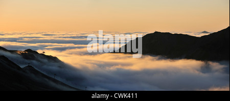 Blick über die Silhouette Sesselbahnen und Berge im Nebel bei Sonnenaufgang gesehen von der Col du Tourmalet, Pyrenäen, Frankreich Stockfoto