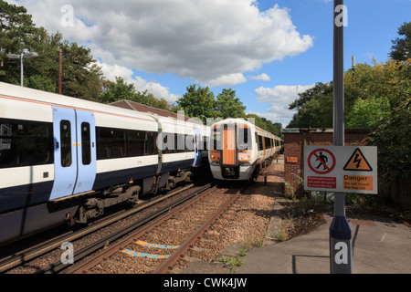 Zwei elektrische Schnellzüge, die Weitergabe von elektrifizierten Eisenbahn mit Gefahr unterschreiben Warnung nicht an die Gleise überqueren. England-UK Stockfoto