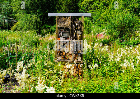 Ein Fachwerk Insektenhaus konstruiert aus Stroh, Ziegelsteine, Protokolle, Rinde und Pappe inmitten einer natürlichen Garten voller Wildblumen Stockfoto
