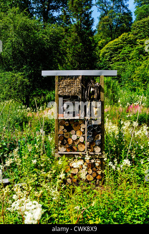 Ein Fachwerk Insektenhaus konstruiert aus Stroh, Ziegelsteine, Protokolle, Rinde und Pappe inmitten einer natürlichen Garten voller Wildblumen Stockfoto