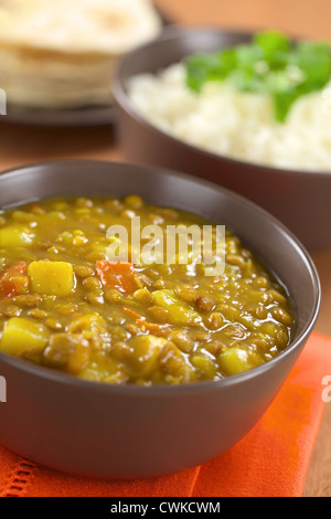 Schüssel mit würzige indische dal (Linsensuppe) Curry mit Karotten und Kartoffeln, Reis und Chapati Fladenbrot in der Rückseite vorbereitet Stockfoto