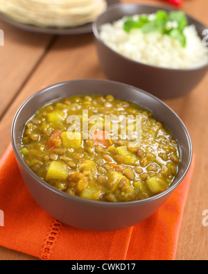 Schüssel mit würzige indische dal (Linsensuppe) Curry mit Karotten und Kartoffeln, Reis und Chapati Fladenbrot in der Rückseite vorbereitet Stockfoto