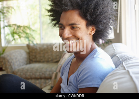 Lächelnder Mann sitzt auf dem Sofa im Wohnzimmer Stockfoto