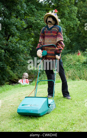 Vogelscheuche Kettlewell Festival Darstellung eines Mannes mit einem Rasenmäher Mähen Stockfoto