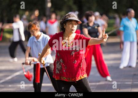 Ältere chinesische Frauen Praxis Schwert Martial Arts trainieren Sie am frühen Morgen im Tempel des Himmels Park im Sommer in Peking Stockfoto