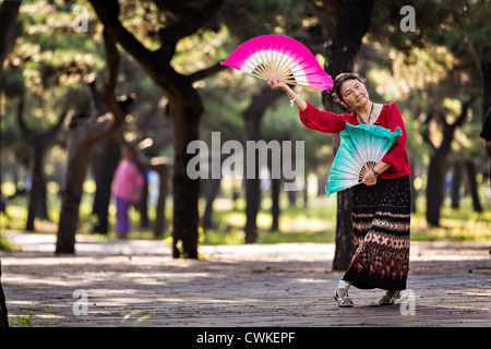 Eine ältere Chinesin Praktiken Tai Chi Fan Tanz Kampfkunst trainieren Sie am frühen Morgen im Tempel des Himmels Park Stockfoto