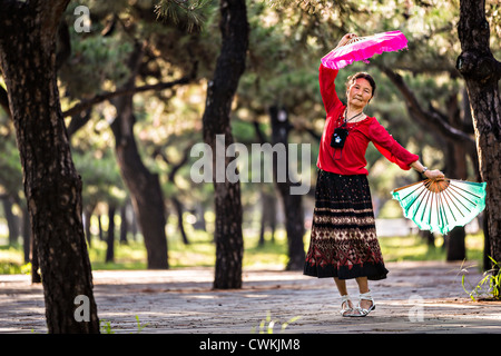 Eine ältere Chinesin Praktiken Tai Chi Fan Tanz Kampfkunst trainieren Sie am frühen Morgen im Tempel des Himmels Park Stockfoto