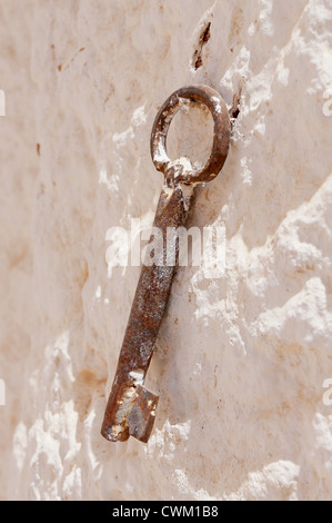 Nahaufnahme von einem rostigen Schlüssel auf einer rustikalen weißen Stein Wand Stockfoto