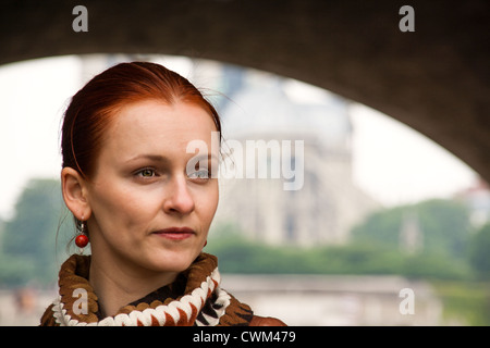 Eine rothaarige Frau, die unter einem Bogen mit der Notre Dame Kathedrale im Hintergrund steht. Stockfoto