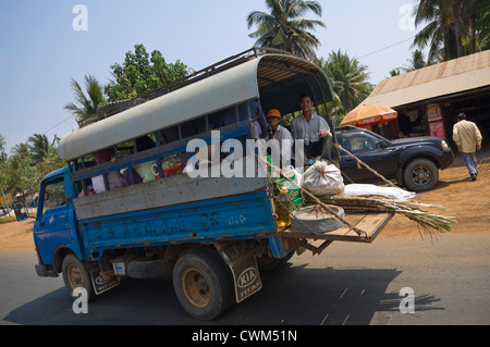 Horizontalen Weitwinkel-Blick auf die Rückseite eines LKW voll mit Menschen und Fracht in eine typische Straßenszene in Kambodscha. Stockfoto