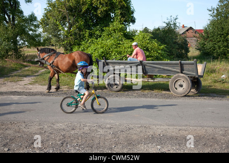 Behelmte polnischer junge mit seinem Fahrrad Dorf Gasse neben Pferd gezeichneten Wagen 4 Jahre. Mala Wola Zentralpolen Stockfoto