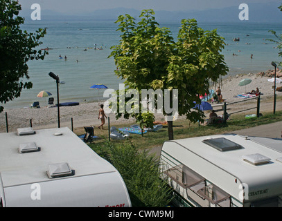 Wohnwagen geparkt neben dem Strand am Gardasee, Camping Lido, Pacengo, Italien, an einem heißen Sommertag im August Stockfoto