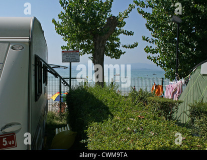 Wohnwagen geparkt neben dem Strand am Gardasee, Camping Lido, Pacengo, Italien, an einem heißen Sommertag im August Stockfoto