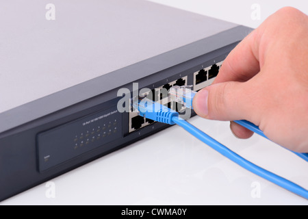 Hand einen rj45-Stecker einstecken an einen Netzwerkhub Stockfoto