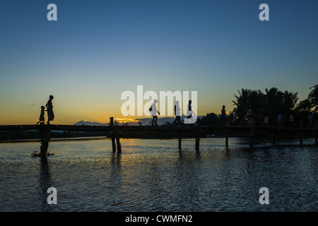 Madagassen der ethnischen Betsimisaraka Überquerung des Flusses durch die hölzerne Brücke bei Sonnenuntergang Stockfoto