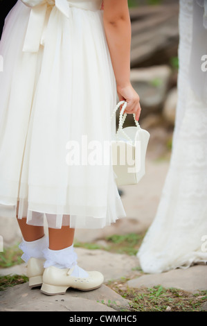 Unteren Bereich des jungen Blumenmädchen in hübsches Kleid tragen eine Geldbörse auf eine Hochzeit im Freien. Stockfoto