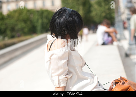 Paris, Frankreich - eine junge Frau Musik hören mit Kopfhörern außerhalb Stockfoto