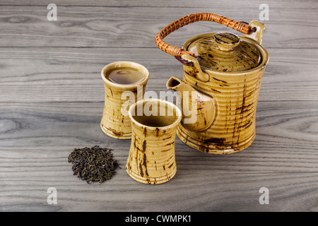 Frische Kanne grüner Tee mit getrockneten grünen Tee Blätter und Tassen auf weiße Asche Holz Hintergrund Stockfoto