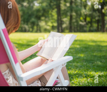 USA, New Jersey, Mendham, Frau sitzen auf Liegestuhl und Buch Stockfoto