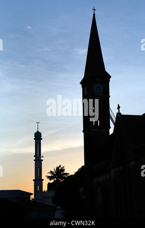 Glockenturm der anglikanischen Kathedrale auf dem Gelände des ehemaligen Sklavenmarkt und Moschee Minarett in Stonetown, Sansibar, Tansania Stockfoto