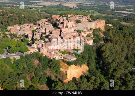 LUFTAUFNAHME. Mittelalterliches Dorf auf einer rot-ockerfarbenen Lehmklippe. Roussillon, Vaucluse, Provence, Frankreich. Stockfoto