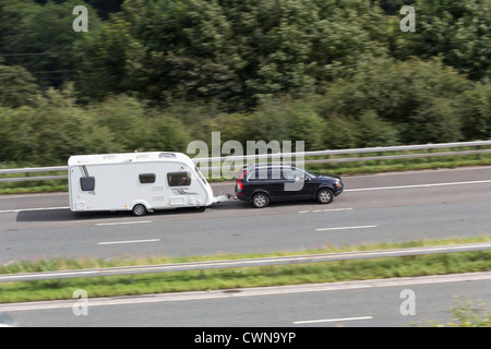 Dunkel blau Kombi Abschleppen eine Swift Charisma 545, 4-Bett Wohnwagen eine Aufwärtstendenz auf die M6 in der Nähe von Tebay Süden unterwegs. Stockfoto