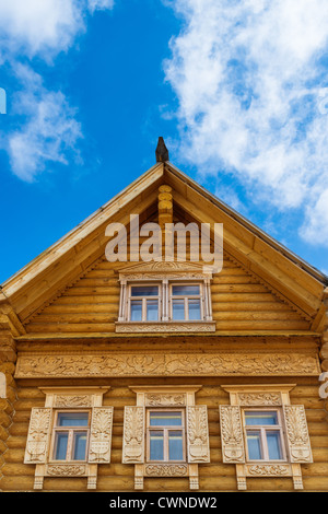 Fragment einer hölzernen Blockhaus mit ornamentalen Fenstern auf dem blauen Himmelshintergrund. Russischen Stil. Stockfoto