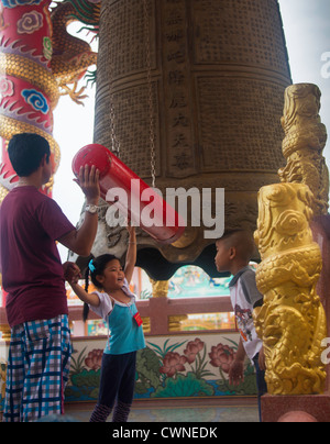 Kinder und Vater schlagen Gebet Gong in Bang Saen chinesische Tempel, Chon Buri, Thailand Stockfoto