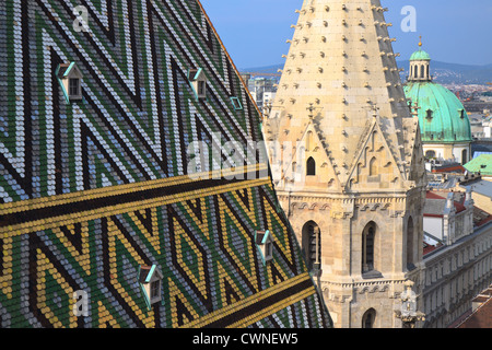 Die farbigen Fliesen Dach des Stephansdom in Wien mit der Kuppel der St.-Peter Kirche (Peterskirche) in der Ferne Stockfoto